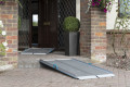 Premium folding wheelchair ramp with anti-slip surface resting on a step in front of a house