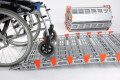 Wheelchair going up ramp with stored ramp beside