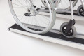 Wheelchair going up pair of telescopic wheelchair ramps 