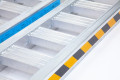 Side of the aluminium loading ramps with warning tape 