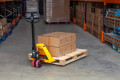 Man moving a pallet using a pallet truck in a warehouse 