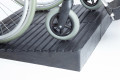 Manual wheelchair going up rubber threshold ramp