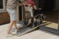 Telescopic bridge wheelchair ramps allowing a manual wheelchair to overcome a threshold