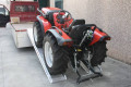 Mower driving up ramps onto flat bed trailer