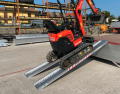 Mini Digger driving up plant ramps resting on flat bed van