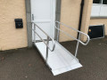 Wheelchair ramp resting on door step with the door close showing the ramp can be left in place