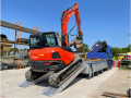 Plant machinery driving up alloy ramps onto van 