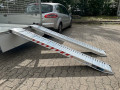 Pair of aluminium loading ramps resting on flat bed trailer 