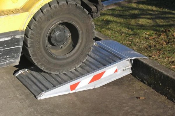 Forklift driving up pair of container ramps 