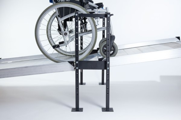 Wheelchair going up two ramps connected by black joining support 