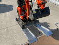 Min-Digger driving up plant ramps resting on flat bed van