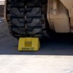 Yellow Checkers wheel chock underneath vehicle tracks 