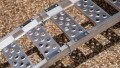 Single aluminium lightweight motorcycle ramp resting on the boot of a vehicle, close up of the grip surface