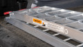 Close up of a single motorbike ramps with support legs resting folded up and stored in the boot of a vehicle