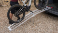 Single motorbike ramp with support legs resting on a vehicle with a push bike being loaded