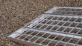 Folding extra wide motorcycle loading ramp resting on car, close up of foot end