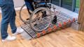 Manual wheelchair on a portable aluminium wheelchair ramp