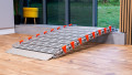 A portable rollable aluminium wheelchair ramp resting on a step
