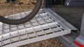 Folding extra wide motorcycle loading ramp resting on car with bike being loaded
