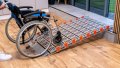 Manual wheelchair on a portable aluminium wheelchair ramp
