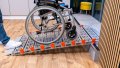 Size view of a manual wheelchair on a portable rollable aluminium wheelchair ramp