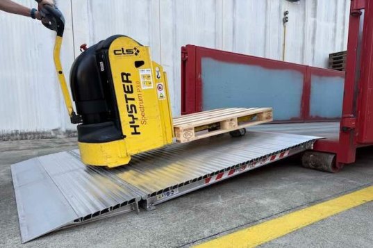 Electric pallet truck driving up container ramp