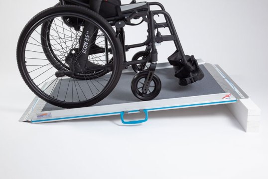 Non-folding wheelchair ramp with self propelled wheelchair going up the ramp 