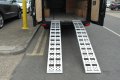 Pair of aluminium loading ramps resting on vehicle 