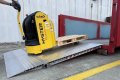 Electric pallet truck driving up container ramp