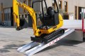 JCB Digger driving down pair of aluminium loading ramps from flat bed trailer 