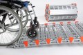 Wheelchair going up ramp with stored ramp beside 