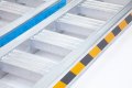 Side of the aluminium loading ramps with warning tape 