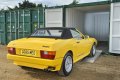 Yellow classic car driving up car ramps into container
