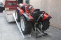 Mower driving up ramps onto flat bed trailer