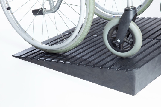 Manual wheelchair on a pair of rubber threshold ramps