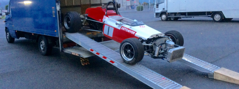 Sports car driving down a pair of loading ramps 