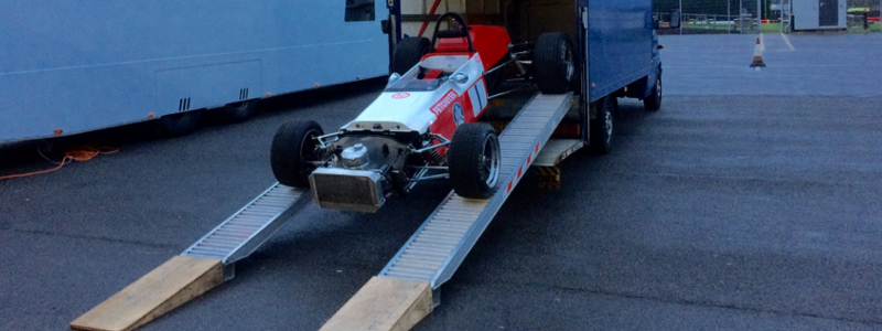 Sports car driving down a pair of loading ramps 