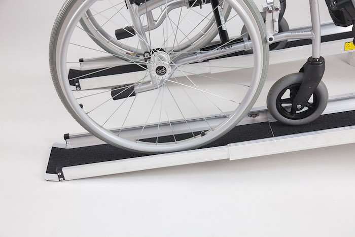 Wheelchair going up a pair of telescopic wheelchair ramps with anti-slip surface
