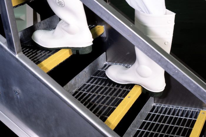 Person walking on yellow stair nosing on metal stair case 