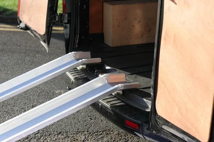 Pair of aluminium loading ramps with edges resting on van