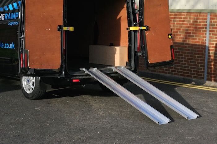 Pair of aluminium van ramps resting on back of van