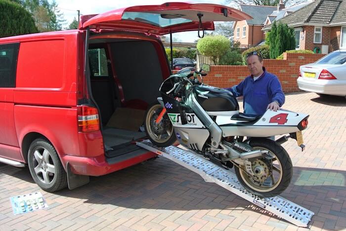 Man pushing motorcycle up ramps