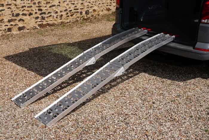 Pair of aluminium loading ramps resting on a van