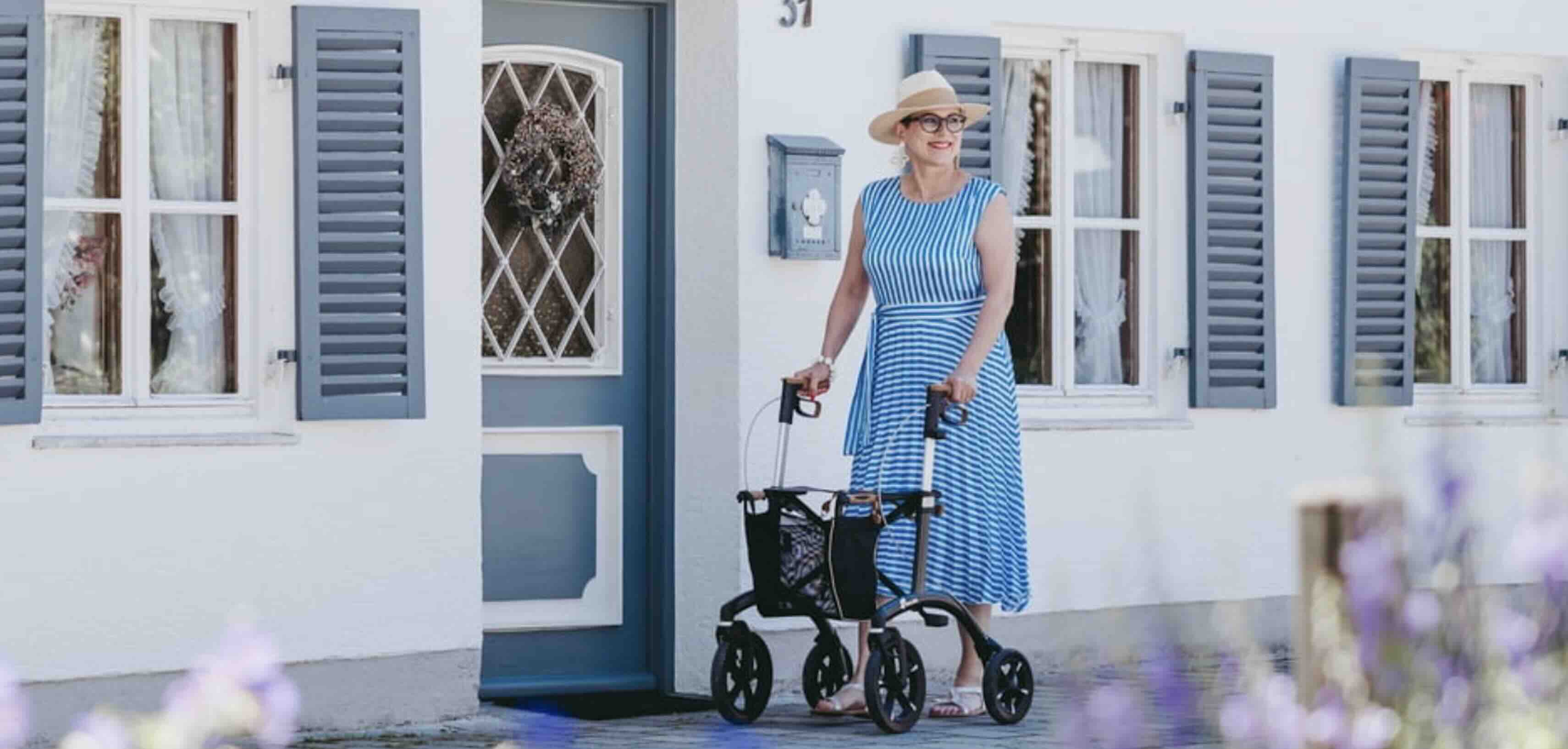 Lady walking in front of houses with Saljol Allround Rollator