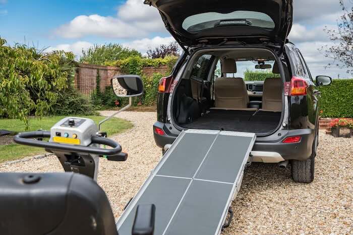 Mobility scooter being loaded into car boot using a ramp