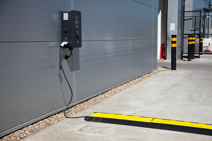 Black and yellow cable protector protecting EV charging cable in car park 