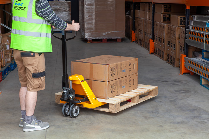 Warehouse worker using manual pallet truck to move a pallet 