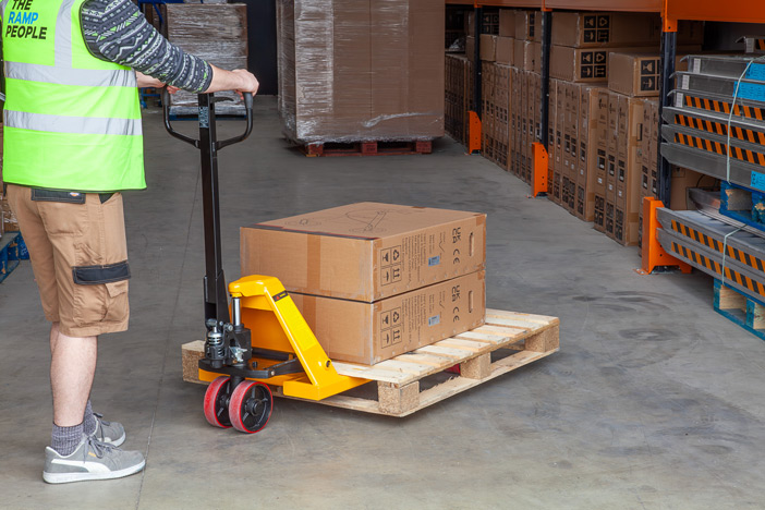 Warehouse worker using manual pallet truck with PU wheels to move a pallet 