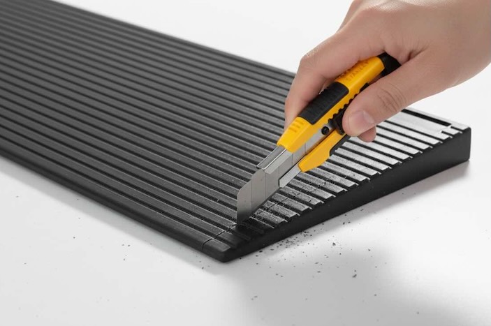 Person using knife to cut rubber threshold ramp 