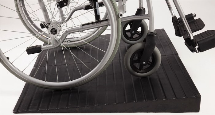 Manual wheelchair going up rubber threshold ramp 
